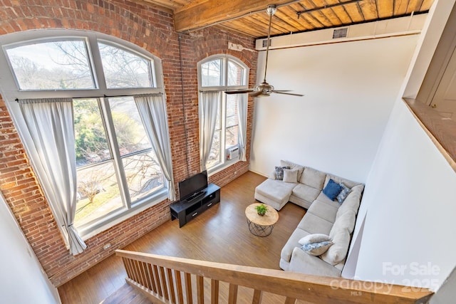 living room featuring wood ceiling, ceiling fan, hardwood / wood-style floors, beam ceiling, and brick wall