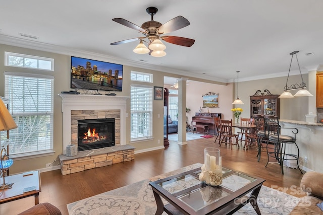 living area featuring visible vents, wood finished floors, and decorative columns