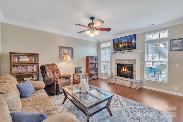 living area with a stone fireplace, crown molding, wood finished floors, and visible vents