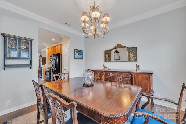 dining area featuring a notable chandelier, wood finished floors, visible vents, and ornamental molding