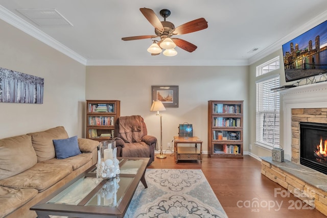 living room with visible vents, a fireplace, wood finished floors, and ornamental molding