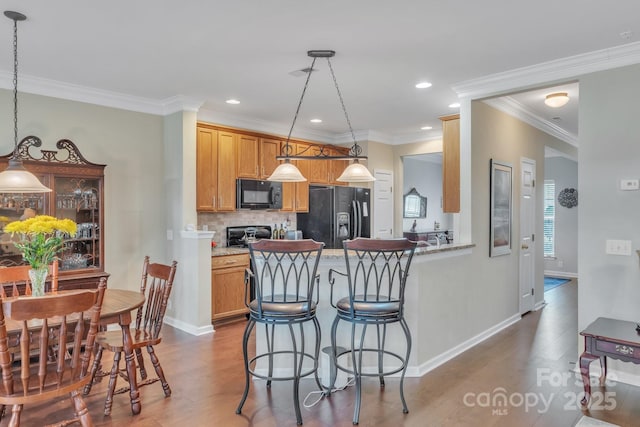 kitchen featuring backsplash, dark wood-type flooring, black appliances, and hanging light fixtures