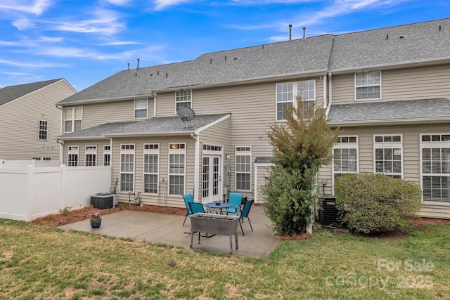 back of property featuring a patio, a lawn, a shingled roof, and fence