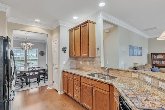 kitchen featuring ornamental molding, a sink, freestanding refrigerator, light wood finished floors, and light stone countertops