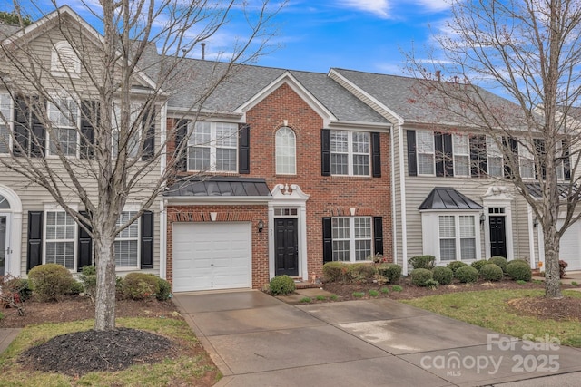 view of front of home featuring driveway, a standing seam roof, a garage, brick siding, and metal roof