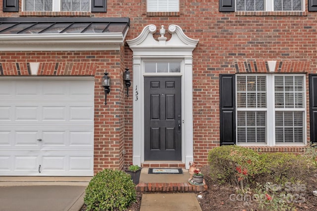 entrance to property featuring brick siding, a garage, metal roof, and a standing seam roof