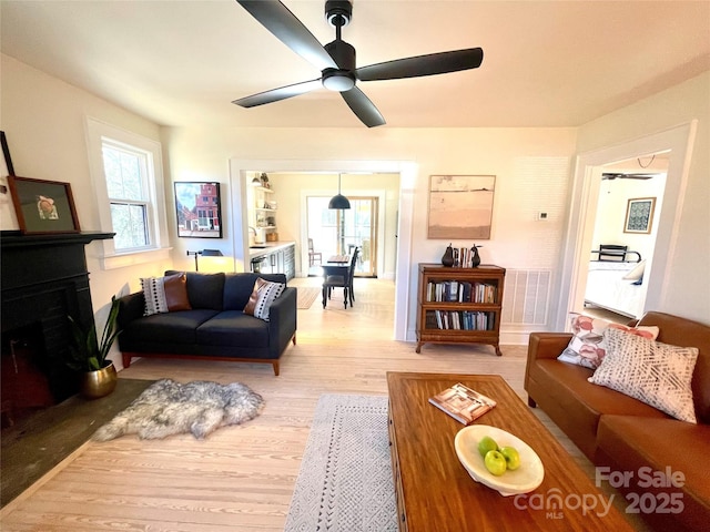 living room with ceiling fan and light hardwood / wood-style flooring