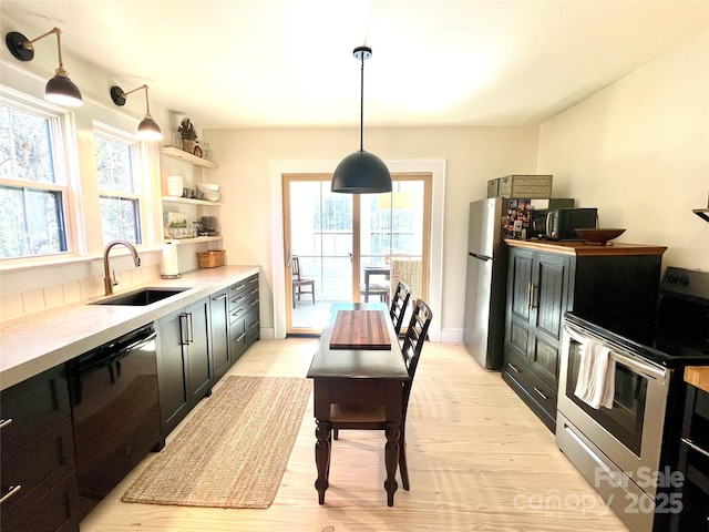 kitchen featuring sink, decorative light fixtures, light hardwood / wood-style flooring, and stainless steel appliances