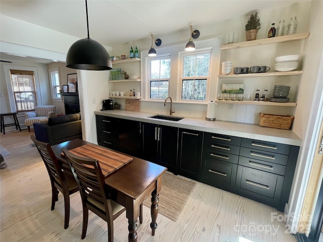 kitchen featuring pendant lighting, light hardwood / wood-style floors, sink, and tasteful backsplash