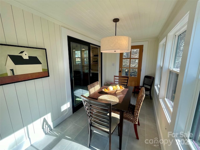 tiled dining room with crown molding, wood ceiling, and wooden walls