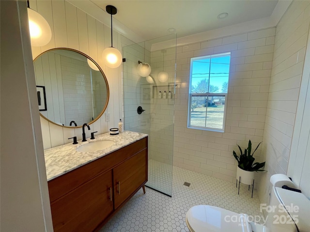 bathroom featuring tile patterned floors, vanity, and a tile shower