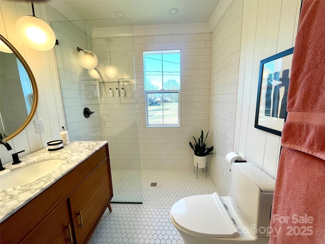 bathroom featuring vanity, toilet, tile patterned flooring, and a tile shower