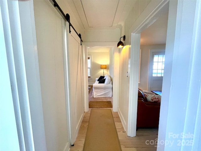 hall with a barn door and light wood-type flooring