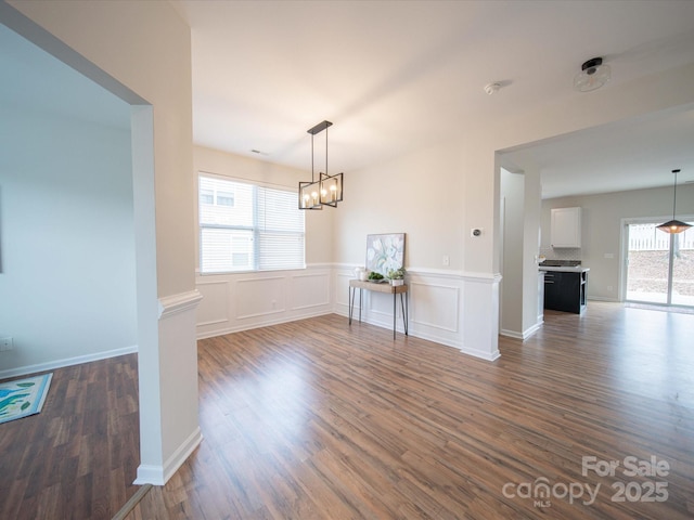 unfurnished dining area featuring an inviting chandelier and dark hardwood / wood-style floors