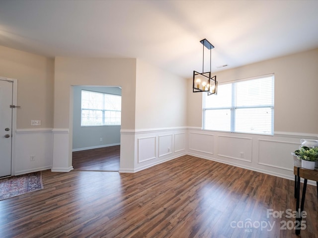 unfurnished dining area featuring dark hardwood / wood-style floors and a notable chandelier