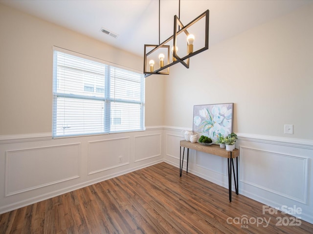 unfurnished dining area featuring dark hardwood / wood-style floors and a chandelier