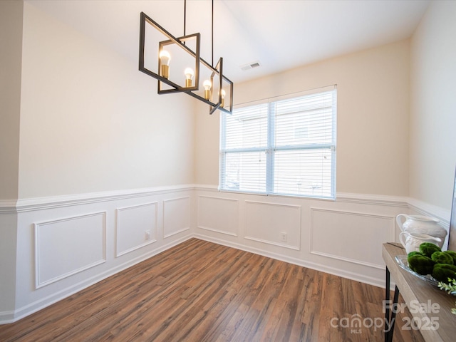 unfurnished dining area with a notable chandelier and dark hardwood / wood-style flooring