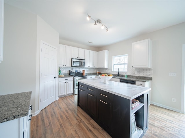 kitchen with backsplash, stainless steel appliances, a center island, and white cabinets