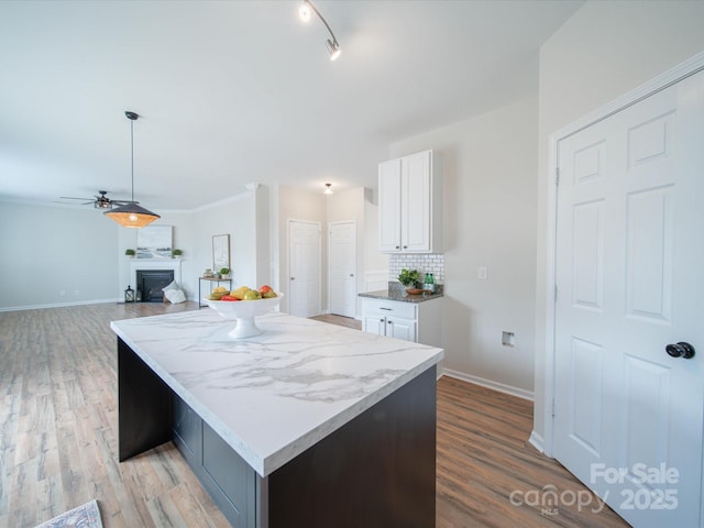 kitchen featuring white cabinetry, tasteful backsplash, light hardwood / wood-style floors, a kitchen island, and decorative light fixtures