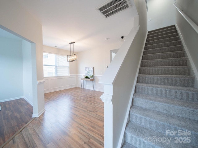 stairs featuring a chandelier and hardwood / wood-style floors