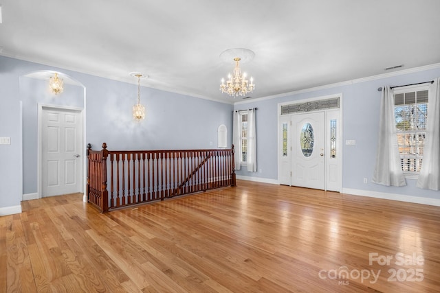 entryway with an inviting chandelier, ornamental molding, and light wood-type flooring