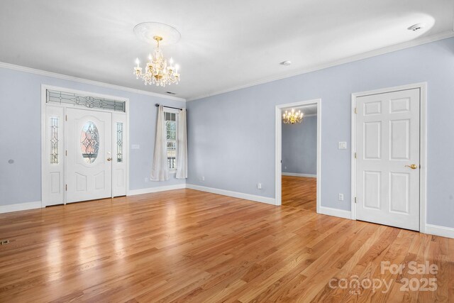 foyer entrance featuring ornamental molding, a notable chandelier, and light hardwood / wood-style flooring