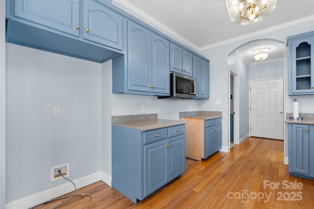 kitchen featuring blue cabinetry, ornamental molding, and light hardwood / wood-style flooring