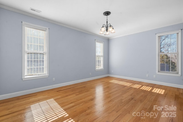 spare room featuring an inviting chandelier, ornamental molding, and light hardwood / wood-style floors