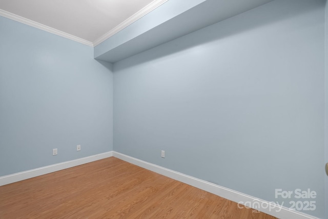 empty room featuring wood-type flooring and ornamental molding