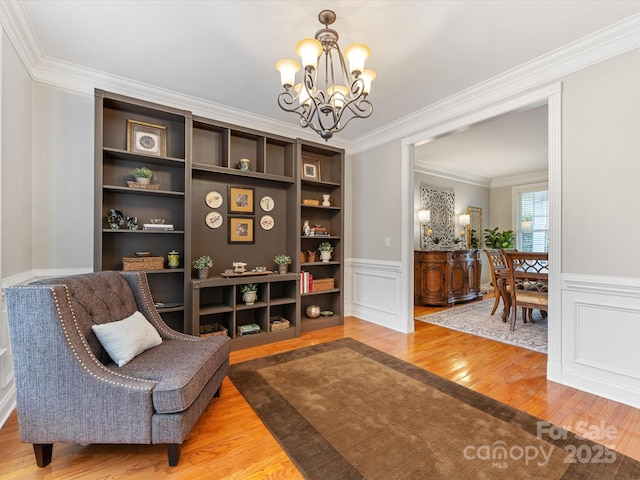 sitting room featuring ornamental molding, hardwood / wood-style floors, and an inviting chandelier