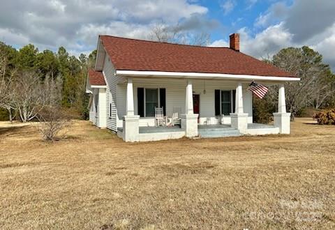 back of house featuring a porch and a lawn