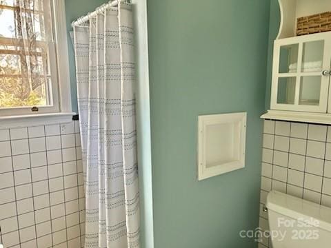 bathroom featuring tile walls and toilet