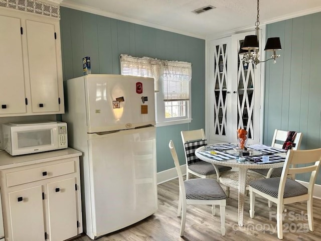 kitchen featuring white cabinetry, hanging light fixtures, white appliances, and ornamental molding