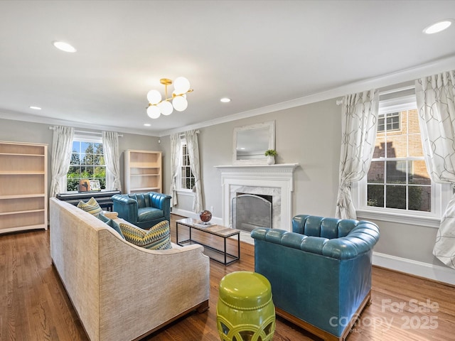 living room with hardwood / wood-style flooring, an inviting chandelier, a high end fireplace, and ornamental molding