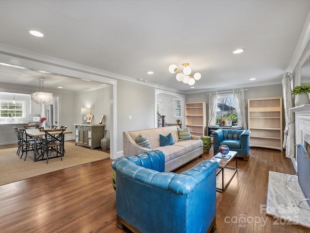 living room featuring crown molding, an inviting chandelier, plenty of natural light, and dark hardwood / wood-style flooring