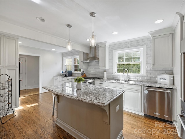 kitchen featuring a center island, dishwasher, a kitchen breakfast bar, wall chimney range hood, and sink