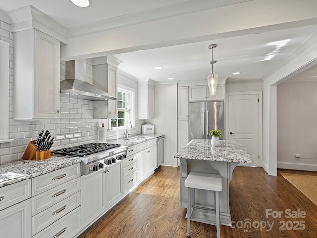 kitchen featuring wall chimney exhaust hood, white cabinetry, a kitchen island, a breakfast bar area, and stainless steel appliances