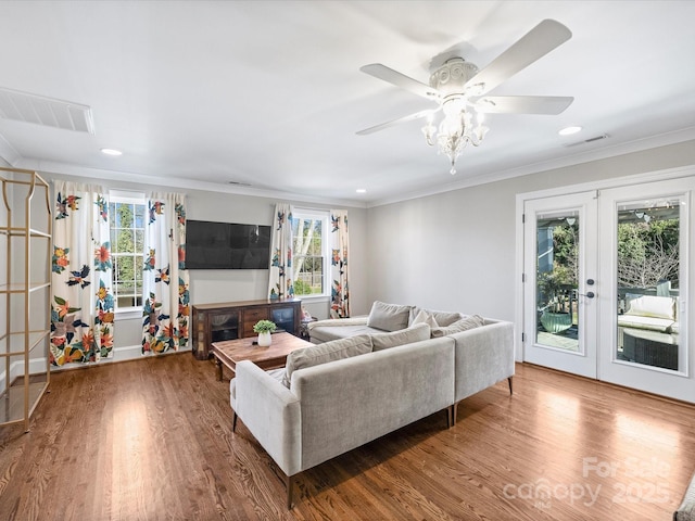 living room featuring wood-type flooring, ornamental molding, a healthy amount of sunlight, and french doors