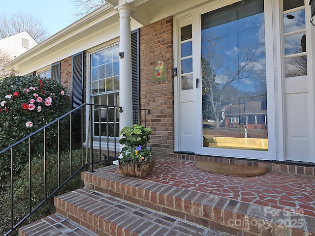 view of exterior entry with brick siding and covered porch