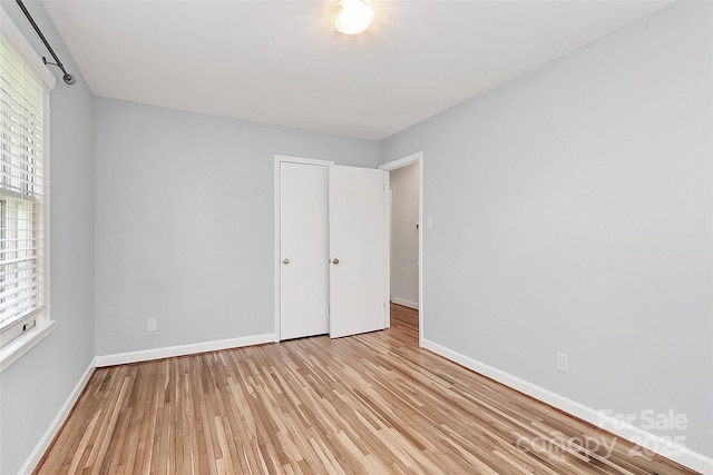 unfurnished bedroom with light wood-type flooring, baseboards, and multiple windows