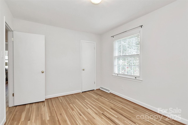 spare room featuring light wood finished floors, baseboards, and visible vents