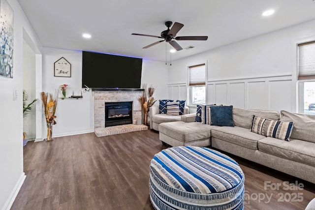 living room featuring ceiling fan, dark wood-type flooring, and a fireplace