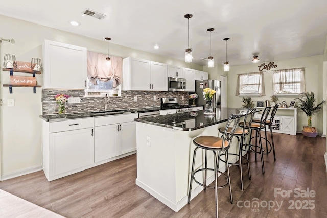 kitchen with sink, white cabinetry, a center island, pendant lighting, and stainless steel appliances