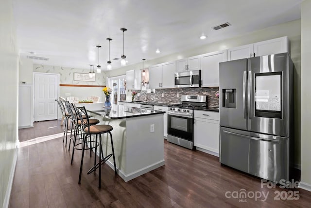 kitchen featuring hanging light fixtures, stainless steel appliances, a center island, and white cabinets