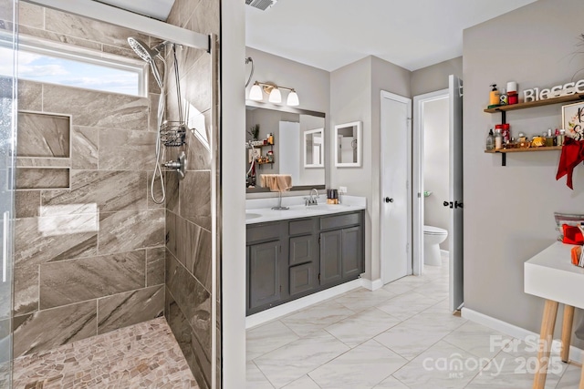 bathroom featuring a tile shower, vanity, and toilet