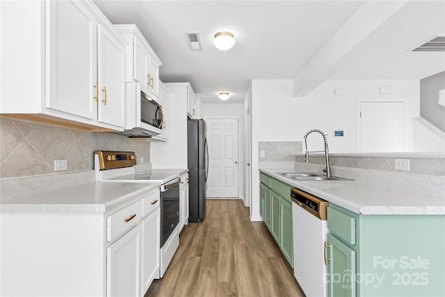 kitchen featuring sink, light wood-type flooring, white cabinetry, green cabinetry, and stainless steel appliances