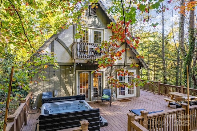 exterior space with a covered hot tub, a deck, french doors, and a balcony