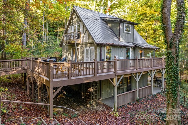 back of house featuring a wooded view, metal roof, and a wooden deck