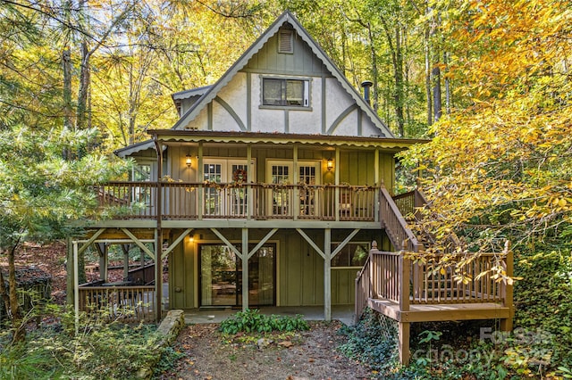 rear view of property with stairs, board and batten siding, a wooden deck, and a patio
