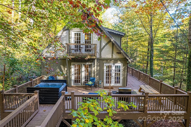 back of property featuring a jacuzzi, a wooden deck, and french doors
